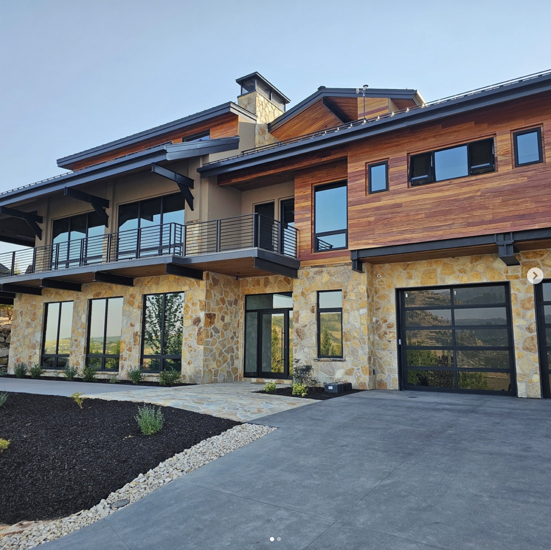 Front facade of a modern mountain residence by Varuna — timber, full-bed stone, and large windows.