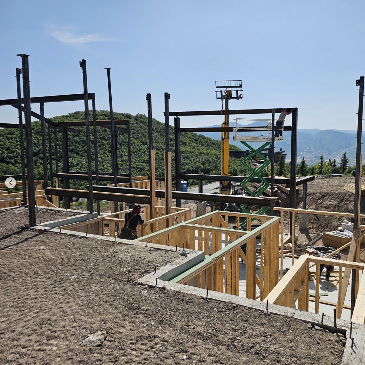 Steel and timber framing during dry-in on a Wasatch hillside Varuna build.